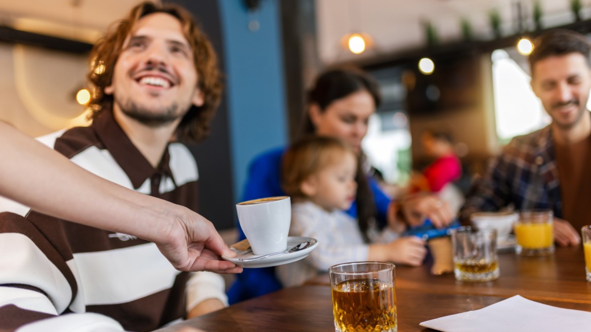 Waiter bringing coffee to his customer in a restaurant.