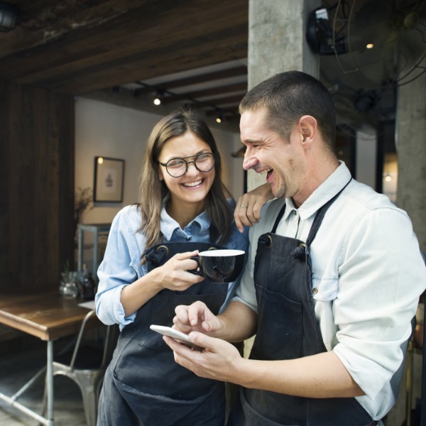 male and female staff smiling in a cafe