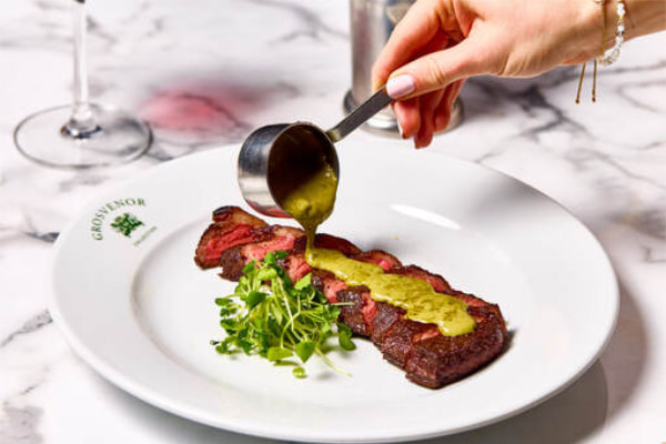 sauce being poured over steak 