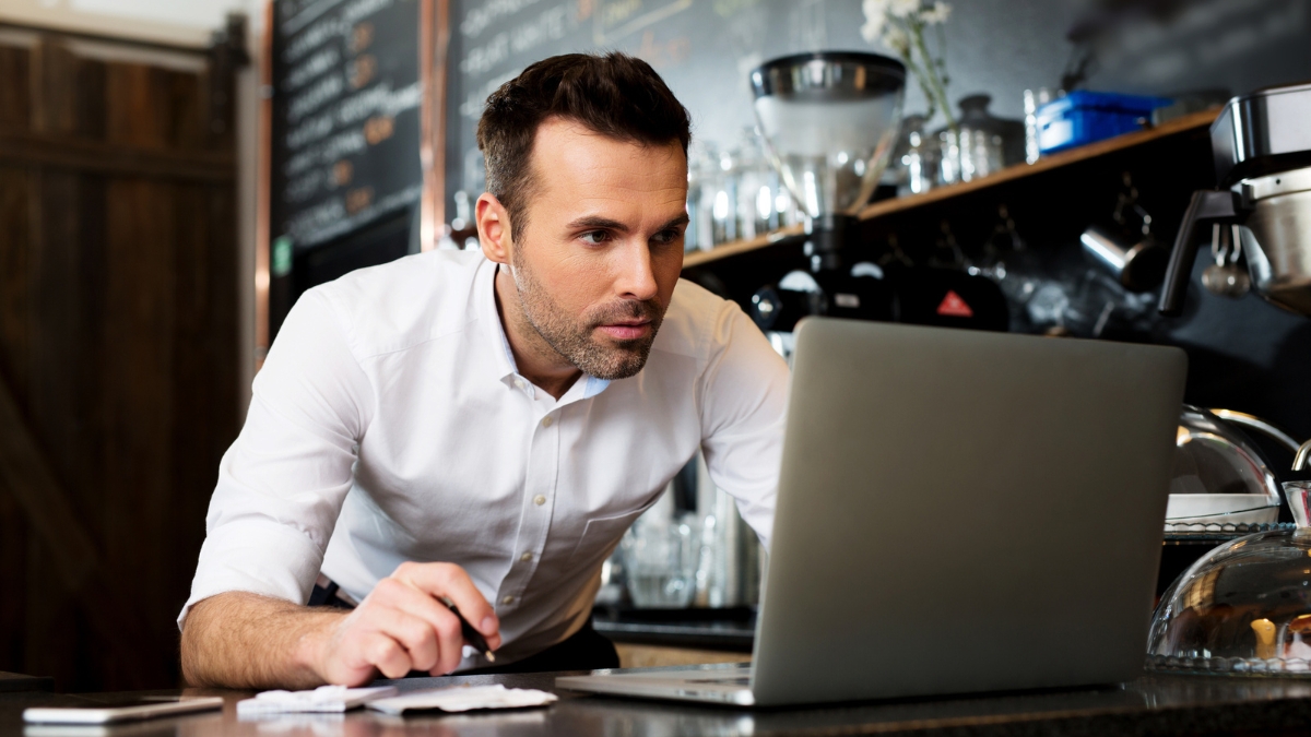 restaurant manager looking at revenue on laptop
